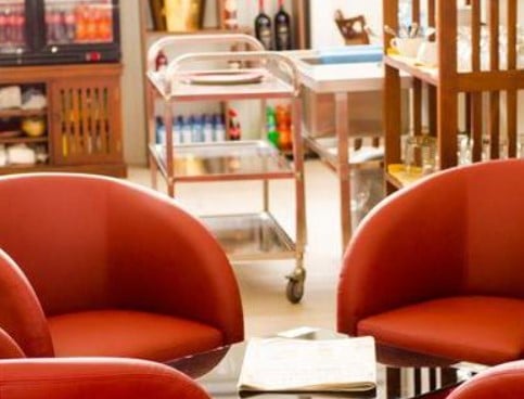 Seating area in Mount Kenya Lounge at Jomo Kenyatta International Airport features curved chairs and a service cart nearby.