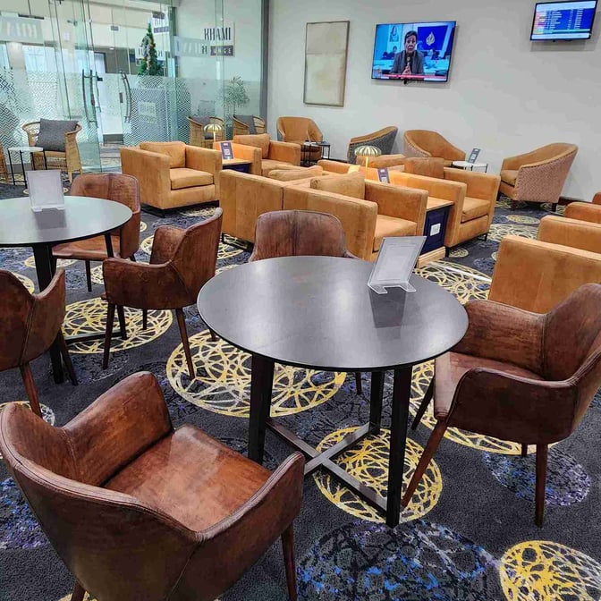 The Khami Lounge at Joshua Mqabuko Nkomo International Airport features a seating area with tables, armchairs, and a television for passenger comfort.