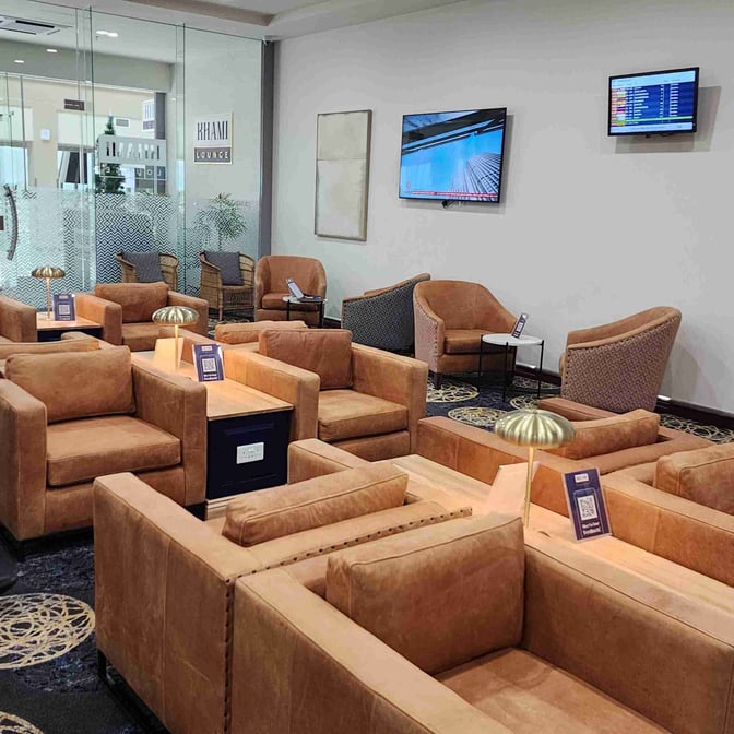 The Khami Lounge at Joshua Mqabuko Nkomo International Airport features comfortable seating with individual tables and power outlets for travelers.