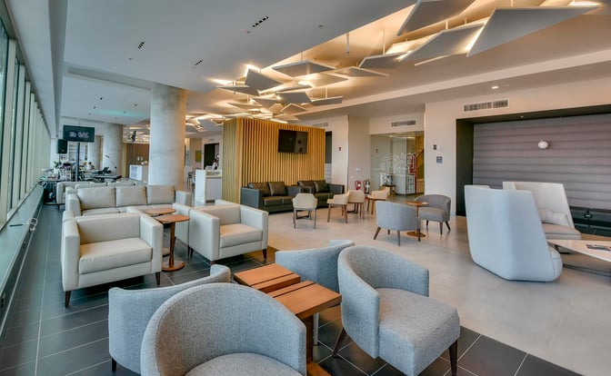 The BAC Credomatic lounge at Juan Santamaría International Airport features various seating options, including armchairs and sofas, with a view of the tarmac.