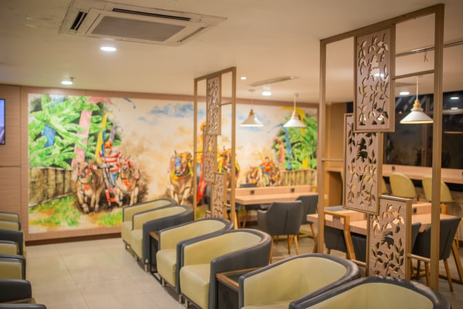 The seating area in Concordia Lounge at Juanda International Airport features comfortable chairs and decorative partitions with a mural backdrop.