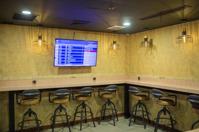The Concordia Lounge at Juanda International Airport features a seating area with bar stools and a wall-mounted flight information display.