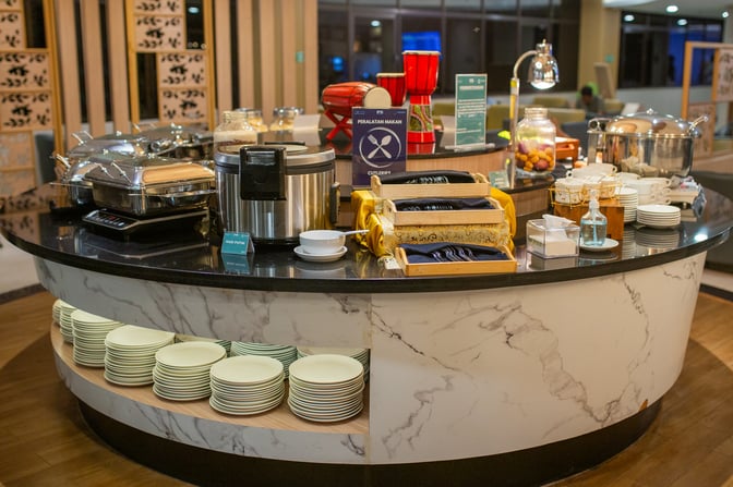 The Concordia Lounge at Juanda International Airport features a self-serve food station with hot dishes, cutlery, and plates available.