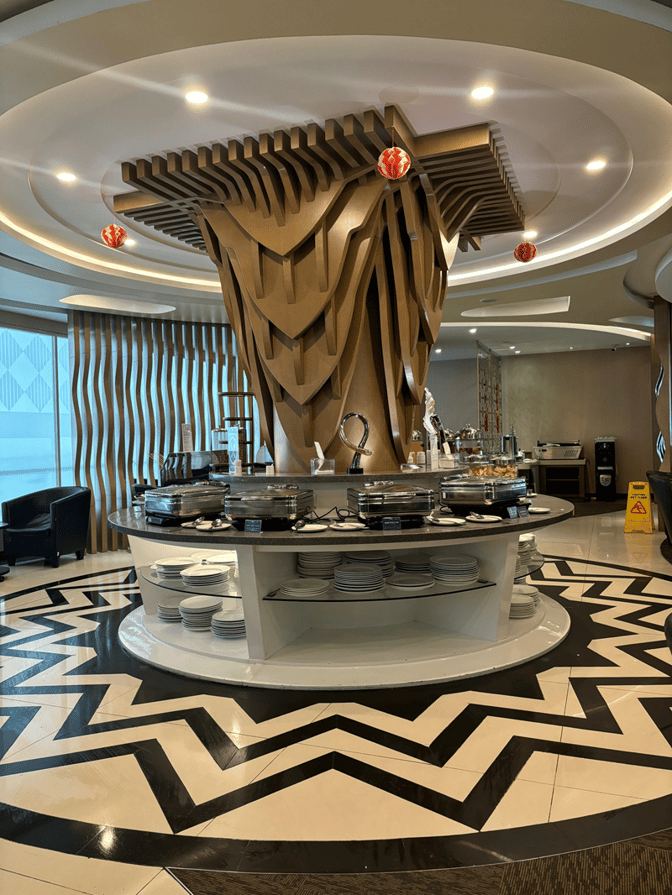 The Concordia Premier Lounge at Juanda International Airport features a central buffet station with self-serve hot dishes and plates.