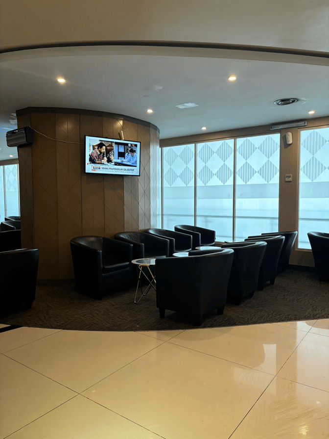Seating area in Concordia Premier Lounge at Juanda International Airport features comfortable chairs and a TV for passenger relaxation.