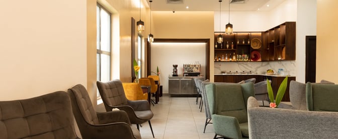 The Serengeti Lounge at Julius Nyerere International Airport features comfortable seating and a bar area with a coffee machine and beverages.