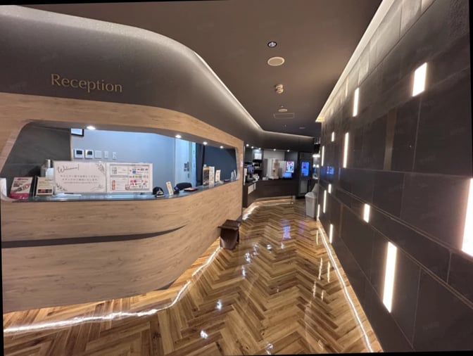 The reception area at SKY Lounge Kagoshima Airport features a service counter with informational displays and a hallway leading to amenities.