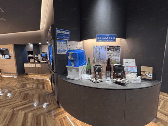 The SKY Lounge at Kagoshima Airport features a beverage station with self-serve drink options and informational displays.