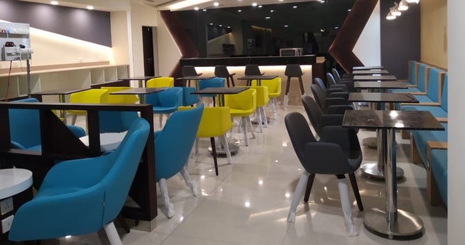 The seating area at Pearl Lounge, Kannur International Airport, features a variety of chairs and tables for dining and relaxation.
