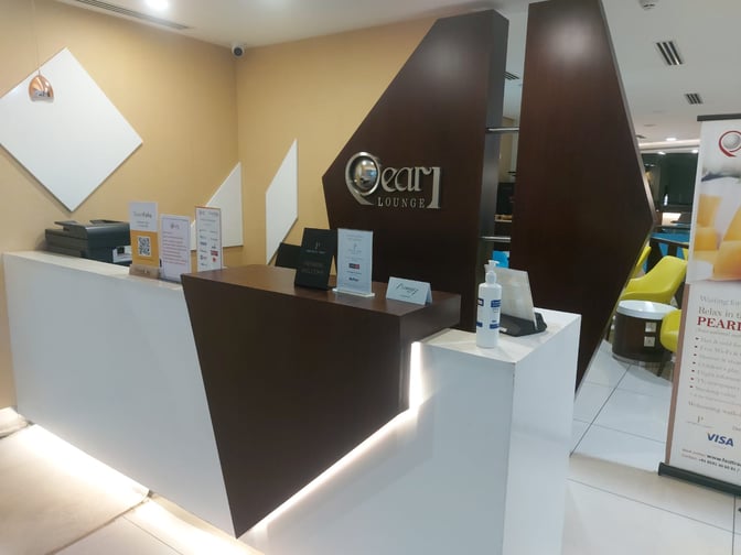 The reception area of the Pearl Lounge at Kannur International Airport features a check-in desk with informational signage and sanitizer.