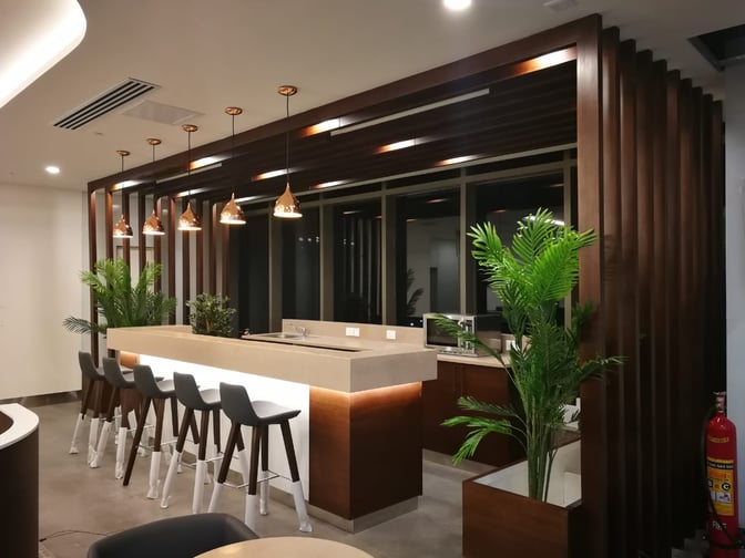 The Pearl Lounge at Kannur International Airport features a bar area with counter seating and pendant lighting, complemented by potted plants.