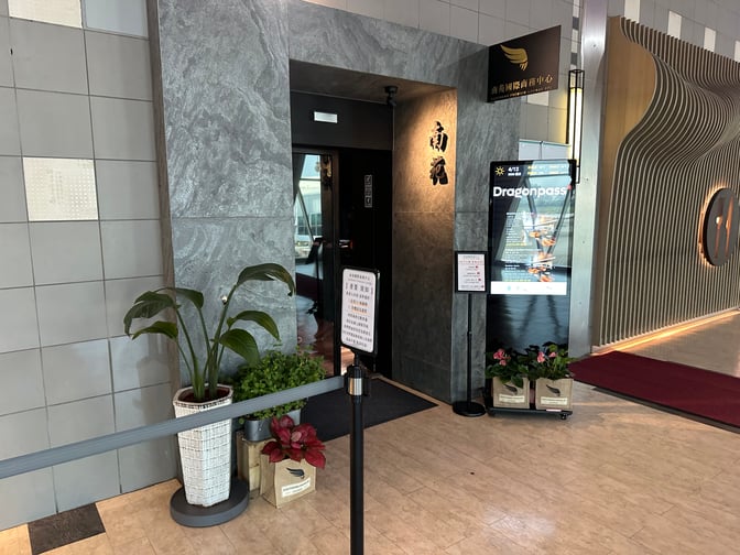 The entrance to the Southern Premium Lounge at Kaohsiung International Airport features signage and potted plants near the doorway.