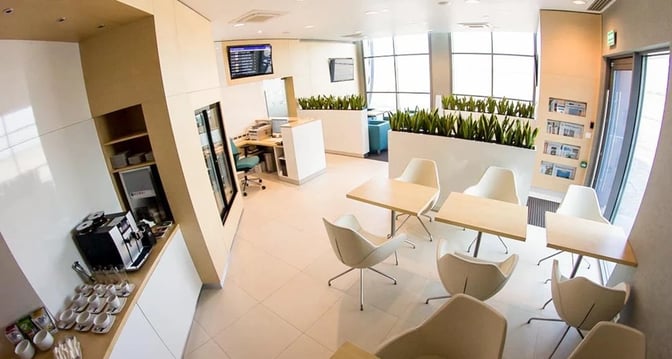 The business lounge at Katowice International Airport features a coffee station, seating area, and flight information display for travelers.