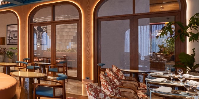 The seating area in the 080 Domestic Lounge at Kempegowda Airport features tables with chairs and a view of the dining section.