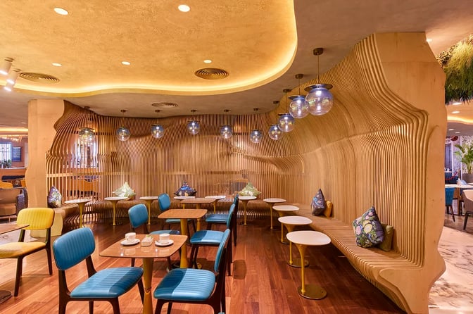 The seating area in the 080 Domestic Lounge at Kempegowda Airport features wooden benches, tables, and chairs for dining and relaxation.