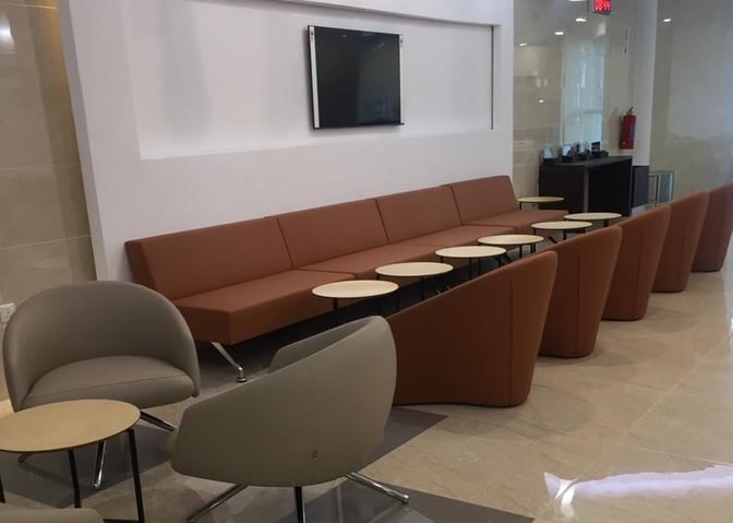 The seating area in Pearl Lounge Zambia features a long sofa with small tables and additional chairs for travelers.