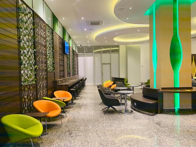 The Pearl Departures Lounge at Kigali International Airport features varied seating options, including chairs and booths, with tables for passenger convenience.