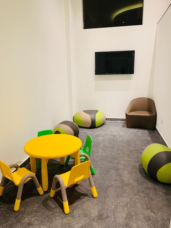 Children's play area in the Pearl Departures Lounge at Kigali International Airport features a small table, chairs, and a wall-mounted TV.