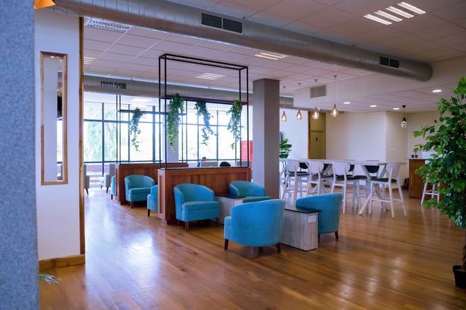 The Twiga Lounge at Kilimanjaro International Airport features comfortable seating areas with armchairs and tables, complemented by high-top communal tables.