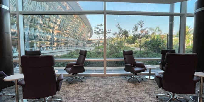 Seating area in Flynas Lounge at King Abdulaziz International Airport offers comfortable chairs and tables with views of the airport's exterior.