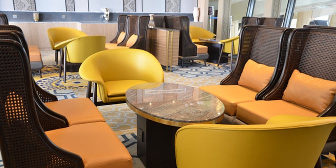 The seating area in the Plaza Premium Lounge at King Abdulaziz International Airport features cushioned chairs and a central table for relaxation.