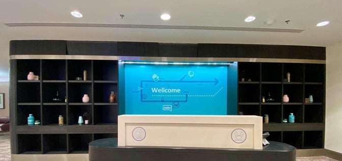 The Wellcome Lounge reception at King Abdulaziz International Airport features a front desk with decorative shelving in the background.