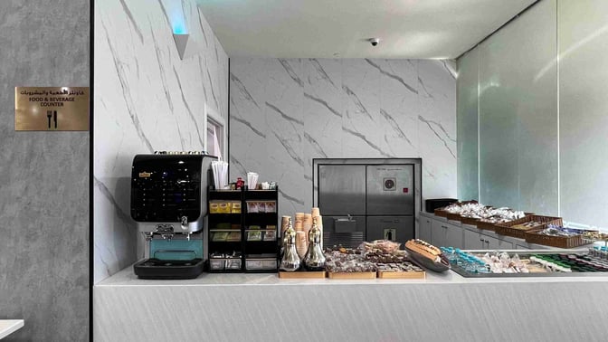 The Flynas Lounge at King Fahd International Airport features a food and beverage counter with a coffee machine and assorted snacks.