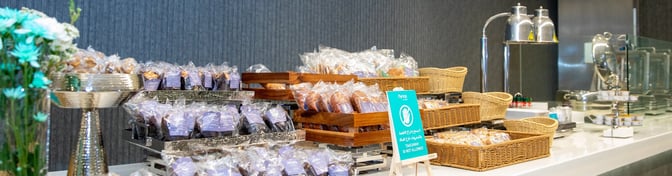 The Flynas Lounge at King Fahd International Airport features a self-serve snack station with packaged items and a takeaway restriction sign.