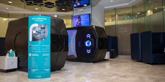 The Flynas Lounge at King Fahd International Airport features sleeping pods and booth seating, with a sign detailing available services.