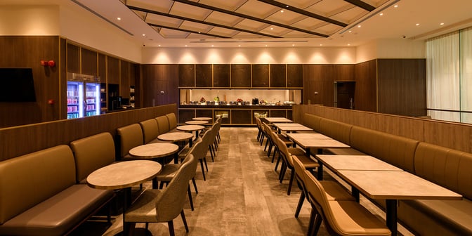 The Plaza Premium Lounge at King Fahd International Airport features a dining area with booth seating and a self-serve food station.