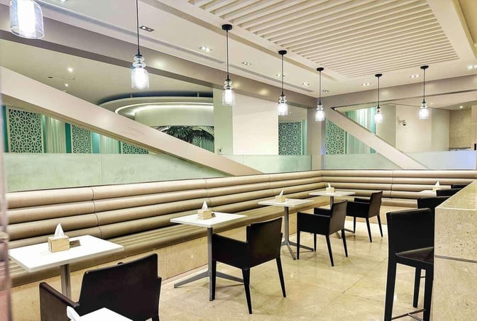 Booth seating in the Wellcome Lounge at King Fahd International Airport provides a comfortable dining area with tables and chairs.