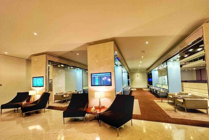 The Wellcome Lounge at King Fahd International Airport features seating areas with lounge chairs, tables, and flight information screens.