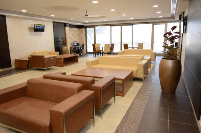 The Pearl Lounge at King Hussein International Airport features seating areas with sofas and tables, and a workspace with computers.