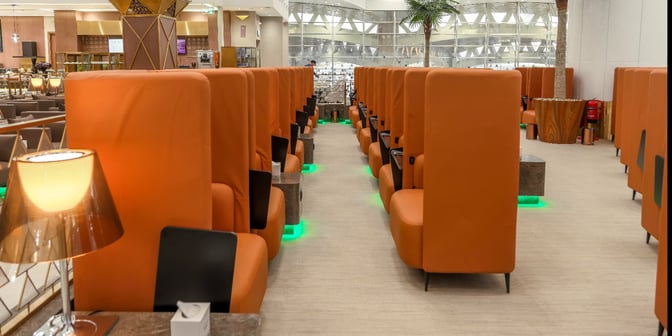 The Hayyak Lounge at King Khalid International Airport features high-backed seating with individual tables, providing a semi-private relaxation area for travelers.