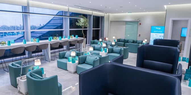 The Flynas Lounge at King Khalid International Airport features a seating area with individual chairs, tables, and a counter with barstools.