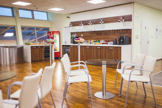 The Kosice Business Lounge features a self-serve beverage area with a variety of drinks and seating for passengers.