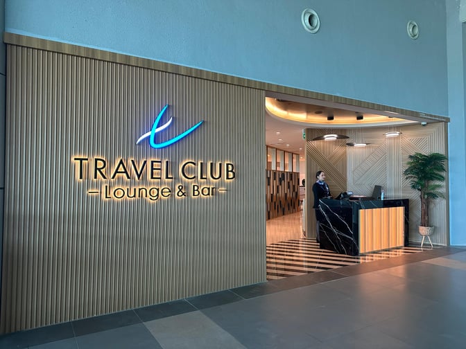 The Travel Club Lounge entrance at Kota Kinabalu International Airport features a reception desk and signage indicating lounge and bar services.
