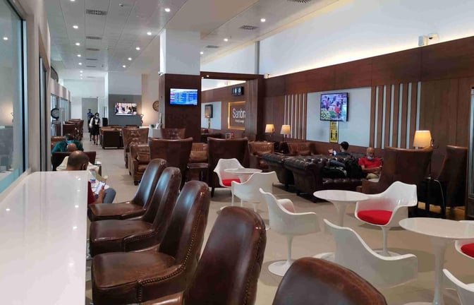 The Sanbra Priority Lounge at Kotoka International Airport features seating areas with leather chairs, tables, and a television for passenger relaxation.