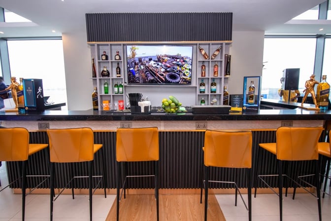 The U Lounge bar at Kotoka International Airport offers a selection of spirits with bar seating and a display screen.