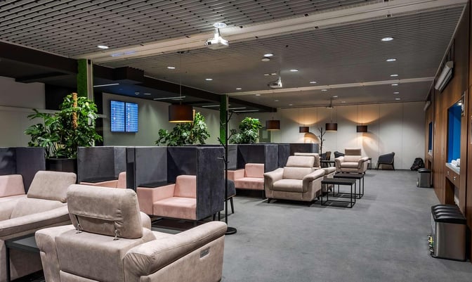 The Krakow Airport Business Lounge features comfortable seating areas with partitioned booths and armchairs, providing a relaxing environment for travelers.