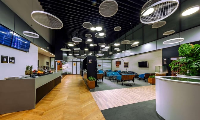 The Krakow Airport Business Lounge features a self-serve food area and a seating section with chairs and tables for travelers.