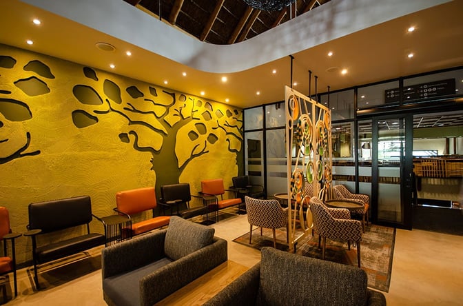 The seating area in the Bidvest Premier Lounge at Kruger Mpumalanga International Airport features armchairs and a decorative partition.
