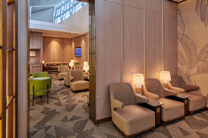 The seating area at Plaza Premium Lounge, Kuala Lumpur International Airport, features comfortable chairs and tables with ambient lighting.