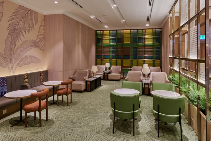 The seating area in Plaza Premium Lounge at Kuala Lumpur International Airport features tables, chairs, and semi-private booths for relaxation.