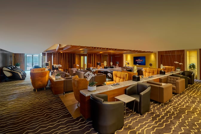 The Sky Suite Airport Lounge at Kuala Lumpur International Airport features comfortable seating areas with massage chairs and a television for entertainment.