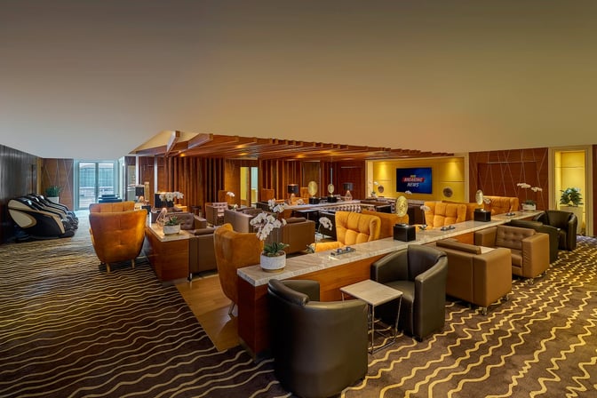 The Sky Suite Airport Lounge at Kuala Lumpur International Airport features comfortable seating areas with massage chairs and a television for entertainment.