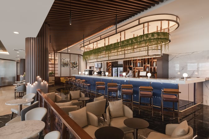 The Travel Club Lounge at Kuala Lumpur International Airport features a bar area with counter seating and adjacent lounge chairs.