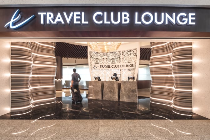 The entrance to the Travel Club Lounge at Kuala Lumpur International Airport features a reception area with check-in counters.