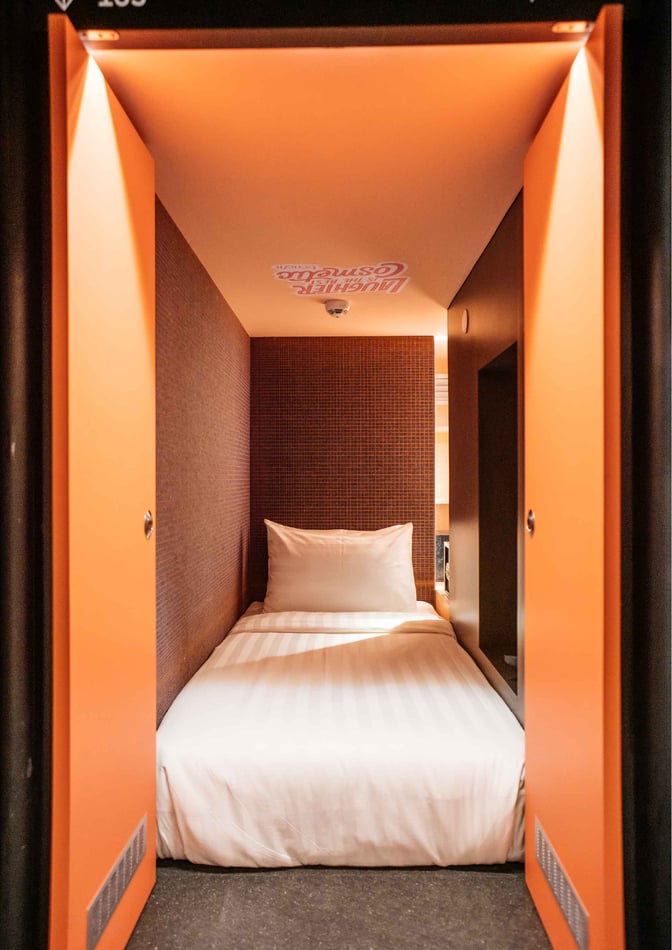 A compact sleeping pod at Capsule Transit KLIA 2 features a single bed with privacy doors for travelers needing rest.