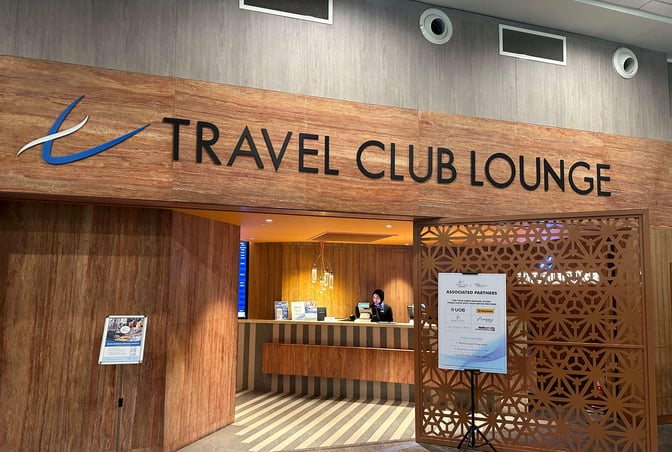 The entrance to the Travel Club Lounge at Kuala Lumpur International Airport features a reception desk and partner information signage.
